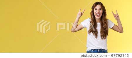 Girl having fun excellent awesome concert enjoy live music show rock-n-roll heavy metal gesture yelling upbeat happy attend cool festival party smiling broadly show tongue daring yellow background 97792545