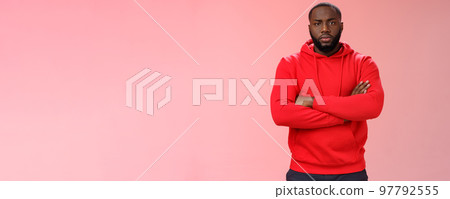 Serious-looking strong black guy security worker cross hands chest confident bossy pose frowning making solid scary look wearing red hooide posing red background, employer controling work 97792555