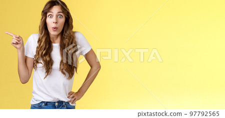 Wow incredible lets click. Impressed surprised pretty european woman long curly hairstyle folding lips intrigued stare astonished wondered awesome cool promo offer pointing left yellow background Wow incredible lets click. Impressed surprised pretty european woman long curly hairstyle folding lips intrigued stare astonished wondered awesome cool promo offer pointing left yellow background 97792565