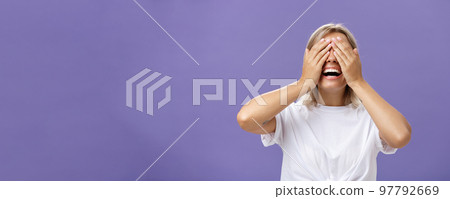 Can I look now. Portrait of excited pleased attractive tanned girlfriend in white t-shirt closing eyes and smiling broadly waiting for boyfriend bring surprising gift over purple background 97792669