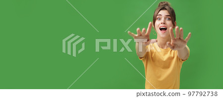 Excited and addicted goog-looking young woman reaching hands forward to camera with reckless look wanting grab something she desire seeing thing she wanted for long time over green background 97792738