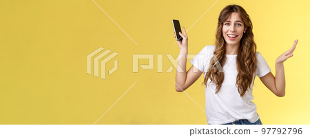 Carefree good-looking lively sociable curly-haired girl having fun wearing wireless earbuds dancing joyfully listening music moving rhythm song hold smartphone raising hands up smiling camera amused Carefree good-looking lively sociable curly-haired girl having fun wearing wireless earbuds dancing joyfully listening music moving rhythm song hold smartphone raising hands up smiling camera amused 97792796