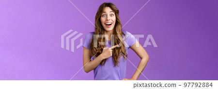 Lively excited enthuasitic good-looking woman curly hairstyle open mouth fascinated look admiration joy share awesome place location pointing left smiling broaldy thrilled purple background 97792884
