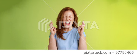 Woman wants win badly. Enthusiastic lucky redhead middle-aged 50s female pleading implore god make dream come true cross fingers good luck wishing closed eyes open mouth excitement green background 97793466