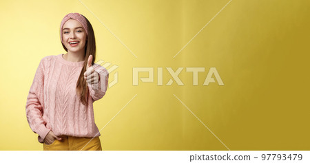 Gestures, emotions and lifestlyle concept. Self-assured positive 20s european woman wearing casual sweater over yellow background showing thumb up gesture, approving, accepting and liking concept Gestures, emotions and lifestlyle concept. Self-assured positive 20s european woman wearing casual sweater over yellow background showing thumb up gesture, approving, accepting and liking concept 97793479