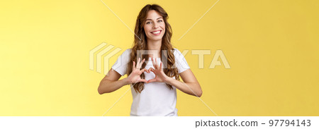 You my valantine. Tender confident adult girl curly hairstyle show heart gesture near chest express romantic sympathy feelings smiling delighted cherish relationship boyfriend yellow background 97794143