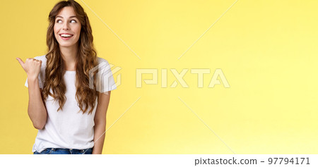 Something interesting right there. Curious lively enthusiastic charming woman glancing pointing thumb left smiling broadly discuss cool event laughing carefree stand yellow background 97794171