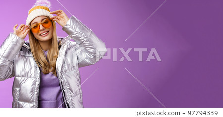 Stylish sassy daring blond european girl acting cool wear stylish sunglasses silver jacket winter hat checking frames nose tilting head cheeky smiling camera enjoying perfect trip friends 97794339