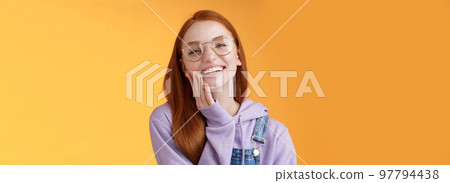 Charismatic happy tender redhead smiling european girl 20s glasses hoodie denim overalls having fun enjoying summer holidays chilly evening laughing joyfully touch pure clear skin, orange background Charismatic happy tender redhead smiling european girl 20s glasses hoodie denim overalls having fun enjoying summer holidays chilly evening laughing joyfully touch pure clear skin, orange background 97794438