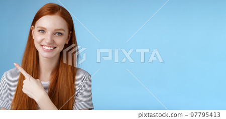 Close-up attractive gentle tender friendly-looking smiling redhead woman show place pointing upper left corner index finger grinning helpful giving choice help find store, standing blue background 97795413