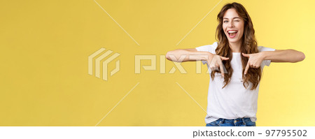 Hey visit my link would not regret. Lively cheeky enthusiastic woman curly long haircut wink sassy smiling broadly show you perfect copy space pointing down bottom promo yellow background 97795502