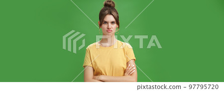 Girl not liking result of work looking displeased and serious at camera, frowning crossing hands against chest, pursing lips from disappointment, being offended over green background Girl not liking result of work looking displeased and serious at camera, frowning crossing hands against chest, pursing lips from disappointment, being offended over green background 97795720