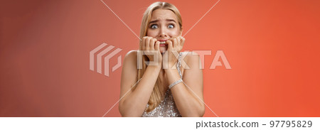 Frightened afraid panicking young cute blond woman biting nails pop eyes scared camera look terrified stunned speechless stare forward standing red background gasping trembling fear Frightened afraid panicking young cute blond woman biting nails pop eyes scared camera look terrified stunned speechless stare forward standing red background gasping trembling fear 97795829