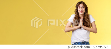 Cute hopeful young caucasian girl stooping hold hands pray smiling hope for pity begging favour plead asking advice say sorry grinning lovely making faithful glances you lend hand yellow background Cute hopeful young caucasian girl stooping hold hands pray smiling hope for pity begging favour plead asking advice say sorry grinning lovely making faithful glances you lend hand yellow background 97795978