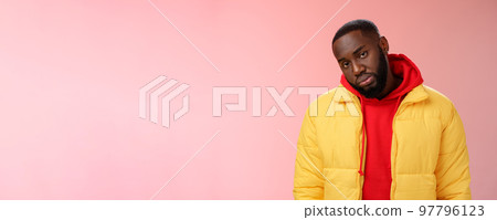 Unimpressed bored ignorant young african bearded man tilt head look scorn uninterest camera listen boring useless information, standing careless in yellow jacket red hoodie, indifferent 97796123