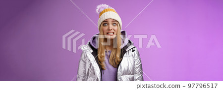 Awkward worried cute timid blond girl in silver jacket hoodie winter hat clench teeth popping eyes camera ooops make mistake standing nervous someone notice, purple background Awkward worried cute timid blond girl in silver jacket hoodie winter hat clench teeth popping eyes camera ooops make mistake standing nervous someone notice, purple background 97796517