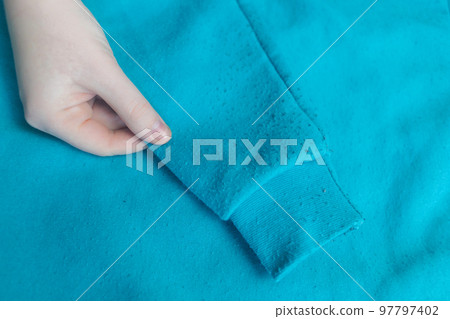 Machine for removing pellets. The girl uses a special device to remove lint from clothes. Restoration of old damaged clothes. Machine for removing pellets. The girl uses a special device to remove lint from clothes. Restoration of old damaged clothes. 97797402