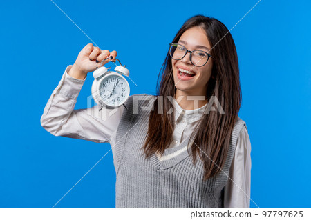 Happy asian student teenager with alarm clock on blue background. Early morning, correct day routine 97797625