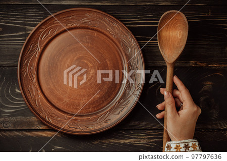 Ukrainian woman sitting in national restaurant and waiting for order. Wooden table, waiting for dish 97797636