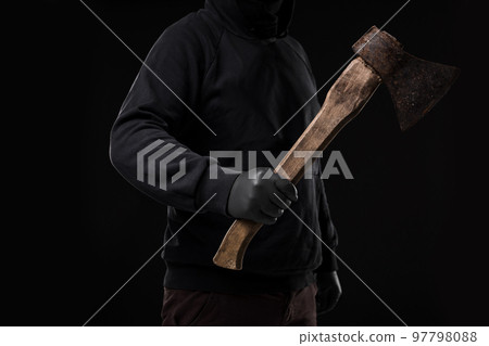 A man in gloves holds an ax in his hands against a black background A man in gloves holds an ax in his hands against a black background 97798088