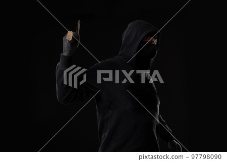 Bandit in black mask with hatchet on black background Bandit in black mask with hatchet on black background 97798090