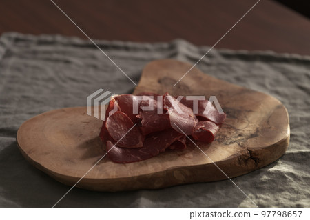 Dried pastrami slices on a wooden board with natural light 97798657