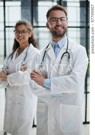 colleagues doctors stand in the lobby of the hospital smiling looking at the camera colleagues doctors stand in the lobby of the hospital smiling looking at the camera 97799907