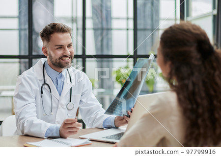 Concentrated male doctor looking at x-ray picture of spine Concentrated male doctor looking at x-ray picture of spine 97799916