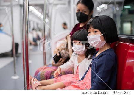 Little girl with surgical mask face protection flu and Virus outbreak in public transportation (skytrain or subway). Concept of New normal lifestyle, Using public transport to travel to school. 97801853