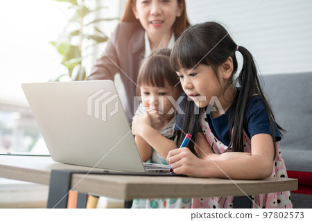 Asian mother with her two grandchildren having fun and playing education games online with a digital computer laptop at home in the living room. Concept of online education and caring from parents. Asian mother with her two grandchildren having fun and playing education games online with a digital computer laptop at home in the living room. Concept of online education and caring from parents. 97802573