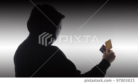 Hacker man and credit cards in hand. Represent credit cards personal data stolen by anonymous man in Black hood shirt. Credit cards data security and Cyber crime digital. Money transection unsecured. 97803815