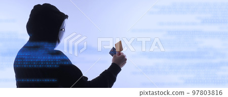 Hacker man and credit cards in hand. Represent credit cards personal data stolen by anonymous man in Black hood shirt. Credit cards data security and Cyber crime digital. Money transection unsecured. 97803816