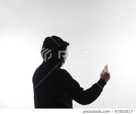 Hacker man and credit cards in hand. Represent credit cards personal data stolen by anonymous man in Black hood shirt. Credit cards data security and Cyber crime digital. Money transection unsecured. 97803817