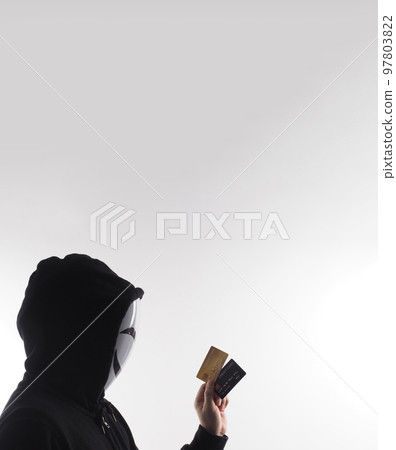 Hacker man and credit cards in hand. Represent credit cards personal data stolen by anonymous man in Black hood shirt. Credit cards data security and Cyber crime digital. Money transection unsecured. 97803822