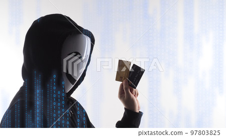 Hacker man and credit cards in hand. Represent credit cards personal data stolen by anonymous man in Black hood shirt. Credit cards data security and Cyber crime digital. Money transection unsecured. 97803825