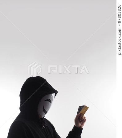 Hacker man and credit cards in hand. Represent credit cards personal data stolen by anonymous man in Black hood shirt. Credit cards data security and Cyber crime digital. Money transection unsecured. 97803826