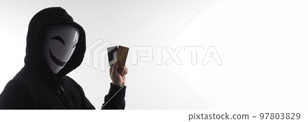 Hacker man and credit cards in hand. Represent credit cards personal data stolen by anonymous man in Black hood shirt. Credit cards data security and Cyber crime digital. Money transection unsecured. 97803829