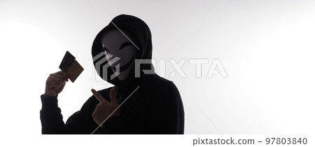 Hacker man and credit cards in hand. Represent credit cards personal data stolen by anonymous man in Black hood shirt. Credit cards data security and Cyber crime digital. Money transection unsecured. 97803840