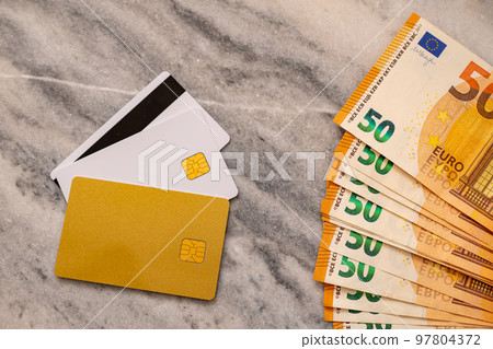 Close-Up Part Of 50 Euro Banknotes And Bank cards. Concept Of Comparing Cash And Non-Cash Money. Close-Up Part Of 50 Euro Banknotes And Bank cards. Concept Of Comparing Cash And Non-Cash Money. 97804372