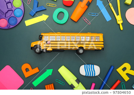 Yellow school bus and stationery on green background, flat lay. Transport for students Yellow school bus and stationery on green background, flat lay. Transport for students 97804650