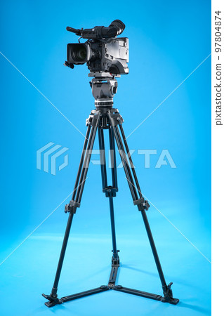 Modern professional video camera on blue background Modern professional video camera on blue background 97804874