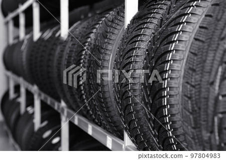 Car tires on rack in auto store, closeup Car tires on rack in auto store, closeup 97804983