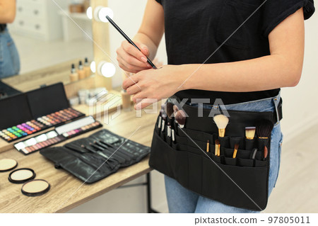 Professional makeup artist with belt organizer full of tools working in studio, closeup Professional makeup artist with belt organizer full of tools working in studio, closeup 97805011