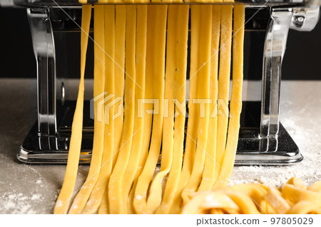Pasta maker machine with dough on grey table, closeup 97805029