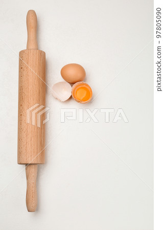 Raw eggs and rolling pin on white table, flat lay. Baking pie 97805090