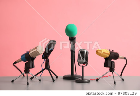 Microphones on table against pink background. Journalist's work 97805129