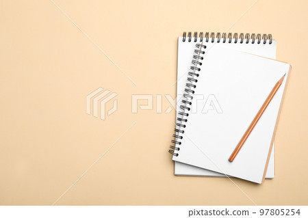 Open notebooks and pencil on beige background, top view. Space for text 97805254