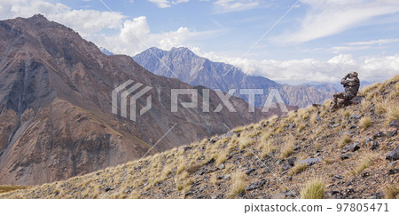 Mountain landscape with huntsman in camouflage who watches through binoculars. 97805471