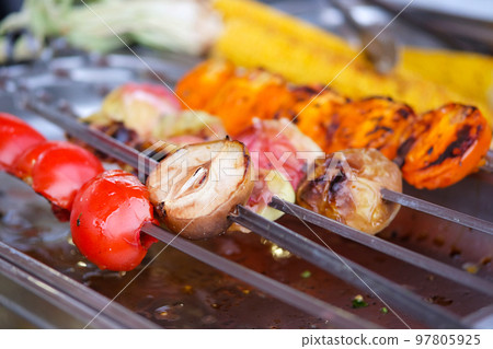 Grilled vegetables close up apples, tomatoes, peppers on skewer on open kitchen food festival event . Street food and outdoor cooking concept. 97805925