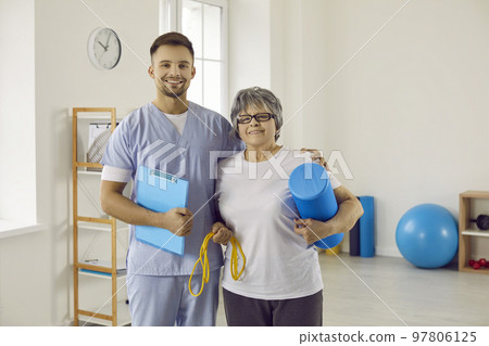Portrait of happy physiotherapist and senior patient standing in physiotherapy room 97806125
